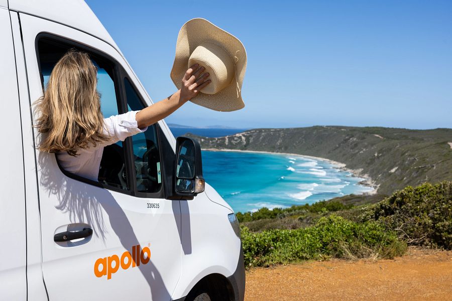 Vrouw zwaait met hoed uit raam van Apollo Euro Plus camper aan de Great Ocean Drive bij Esperance