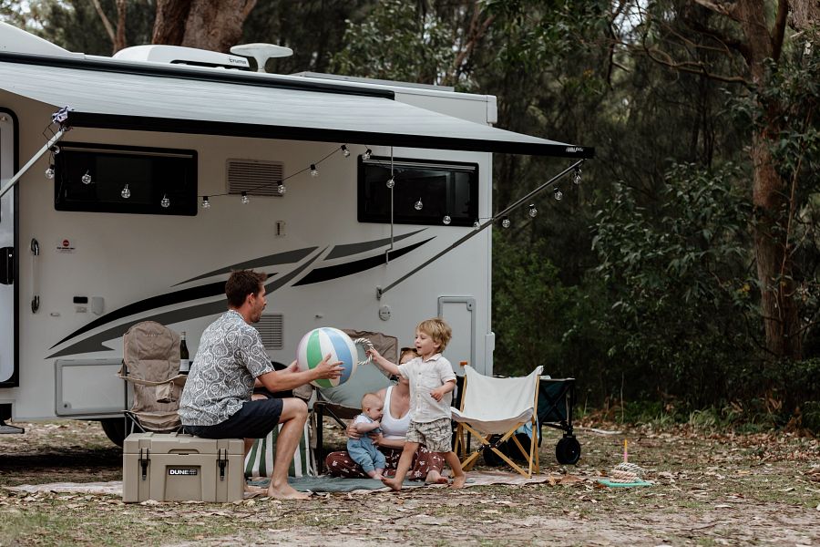 Vader speelt buiten met kind met een opblaasbal voor de camper Apollo Euro Deluxe