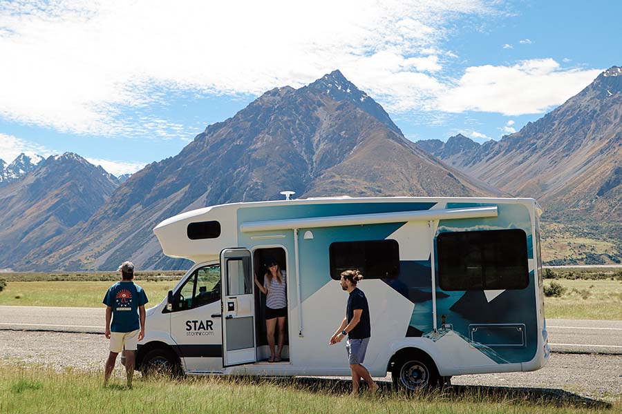 Een vrouw staat in de deuropening van de Star RV Polaris 6 camper en kijkt naar haar vrienden die genieten van het uitzicht