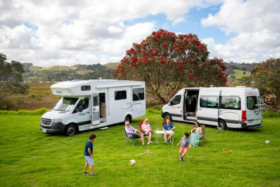 Twee gezinnen verblijven met een Maui River en Apollo Euro Plus camper op een locatie in een glooiende omgeving