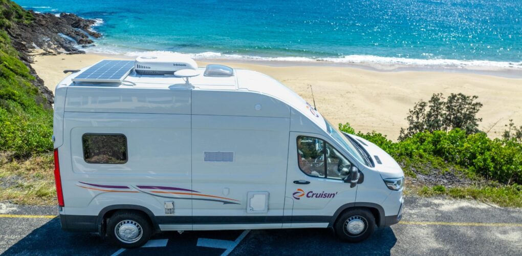 Zijaanzicht van de Cruisin' Rover camper geparkeerd aan het strand