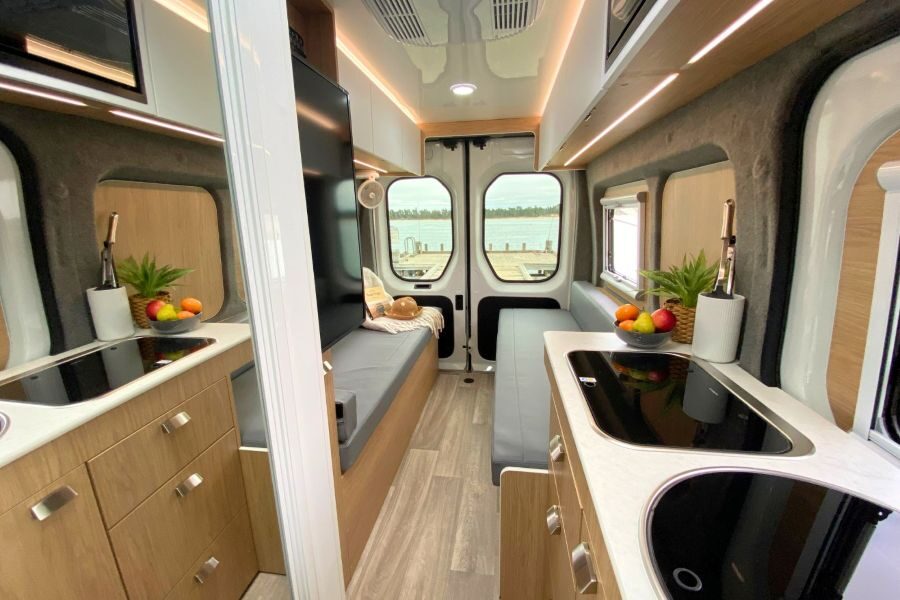 Interieur van de Cruisin' Rover camper met keuken, banken en spiegeldeur van de badkamer