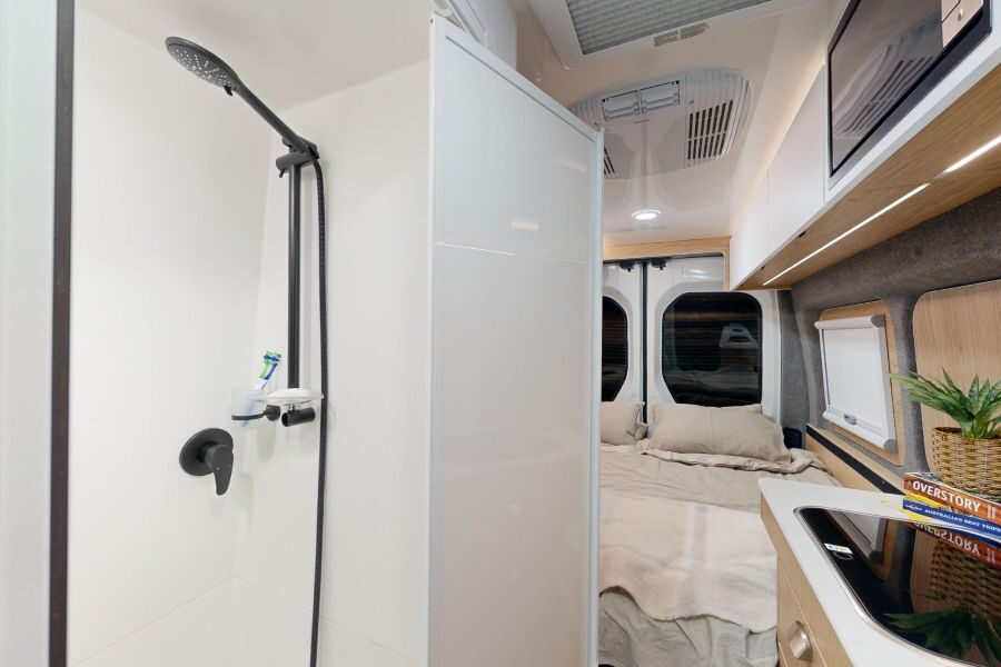 Deur open van de badkamer in de Cruisin' Rover camper met zicht op het bed
