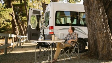 Man zit buiten aan de campingtafel bij een Mighty camper op een camping in Picton