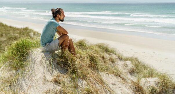 Man zittend bij kust Nieuw-Zeeland