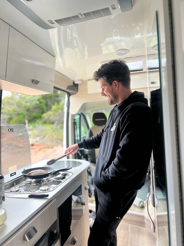 Man staat te koken in de Cruisin' Sandpiper camper