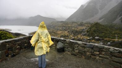 Vrouw loopt met regenjas aan in Nieuw-Zeeland