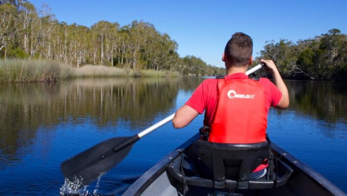 Jongen is aan het kanoën in de Noosa Everglades, zicht van achteren