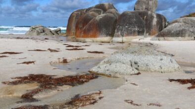 Zicht op grote rode rotsblokken en de zee op Sqeaky Beach in Wilsons promontory