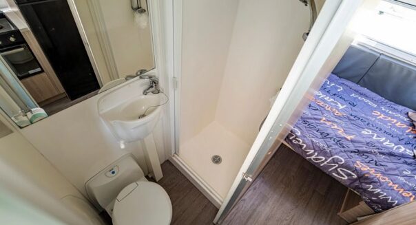 Badkamer met toilet en wastafel met deur open in de Mighty Big Six camper