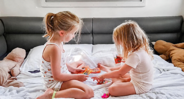 Twee kinderen spelen een spelletje op bed in de Maui Beach camper