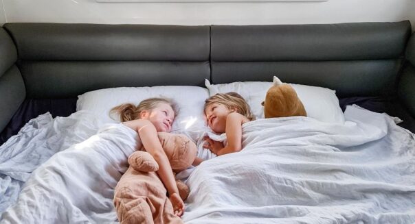 Kinderen liggen met knuffels in bed in Maui Beach camper en zijn nog wakker