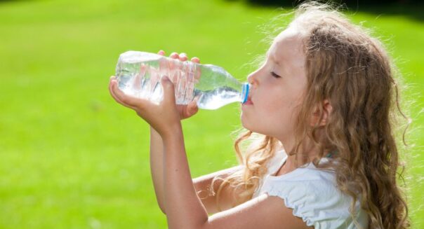 Meisje drinkt buiten uit een plastic fles water