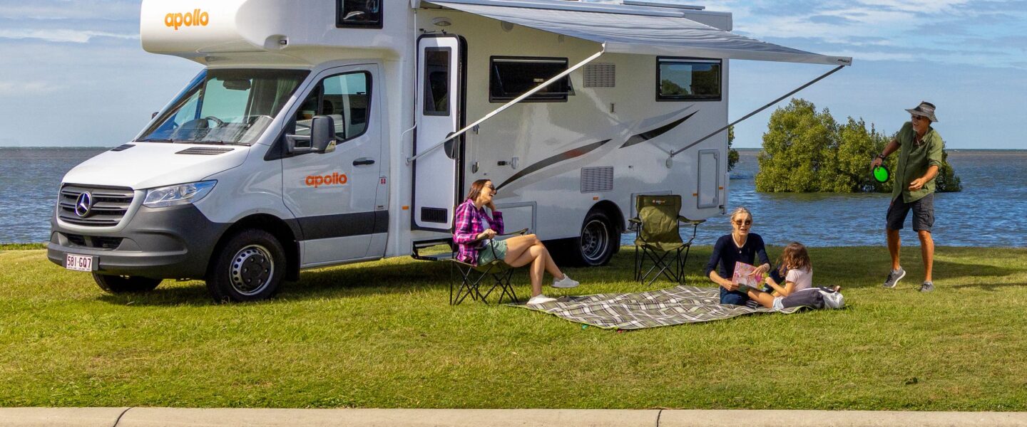 Vader speelt plakbal en moeder leest boekje met kind op kleed voor de Apollo Euro Deluxe camper