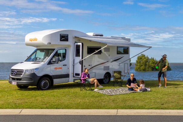 Vader speelt plakbal en moeder leest boekje met kind op kleed voor de Apollo Euro Deluxe camper
