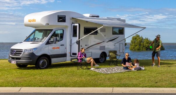 Vader speelt plakbal en moeder leest boekje met kind op kleed voor de Apollo Euro Deluxe camper