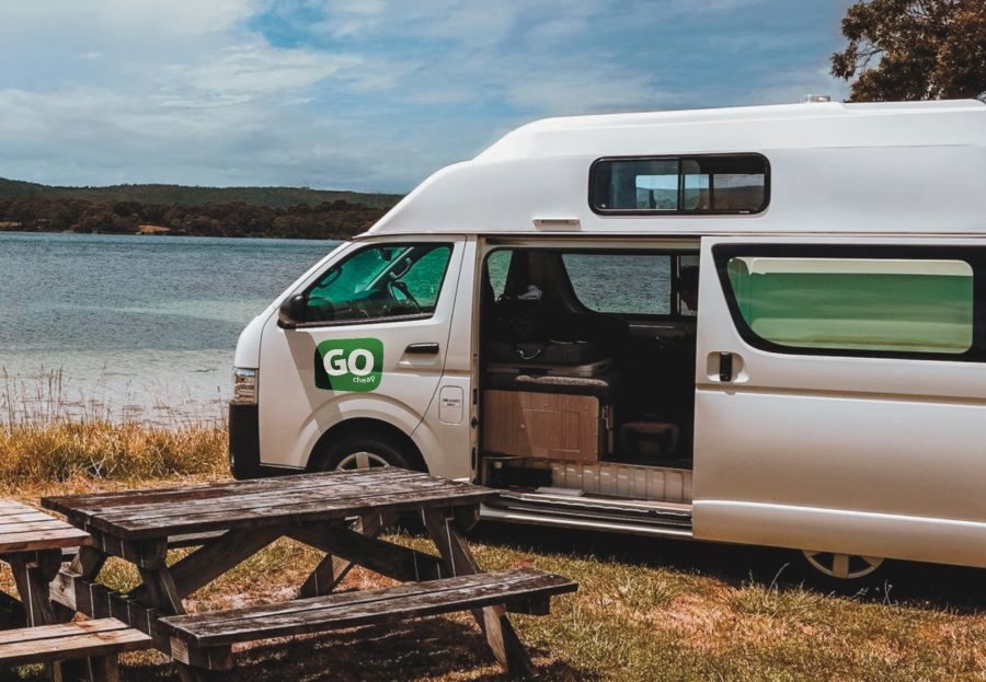 Go Cheap 2 Berth Hitop geparkeerd naast het water, de deur is open en er staat een tafel