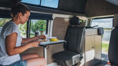 Een vrouw zit binnen aan de tafel van de Go Cheap 4 Berth Hitop