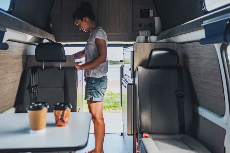 Een vrouw maakt gebruik van de keuken in de Go Cheap 4 Berth Hitop