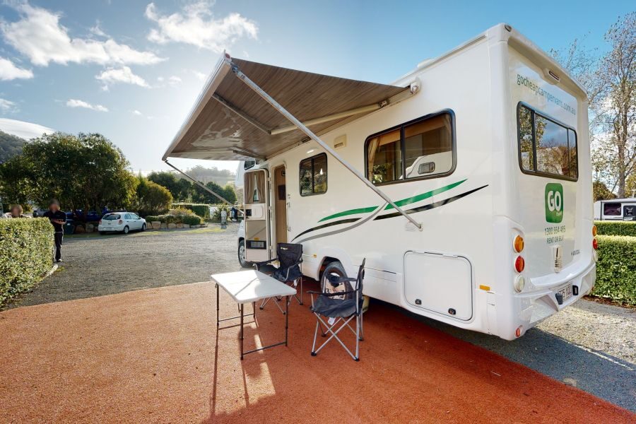 Go Cheap Henty staat geparkeerd op een camping, de luifel is uitgeklapt en de stoelen staan buiten