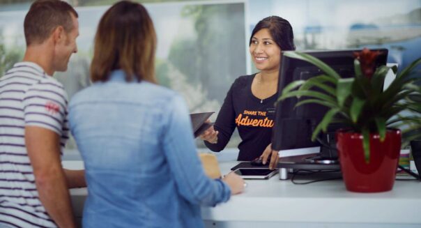 Stel staat aan de balie in gesprek met een medewerker om een camper op te halen