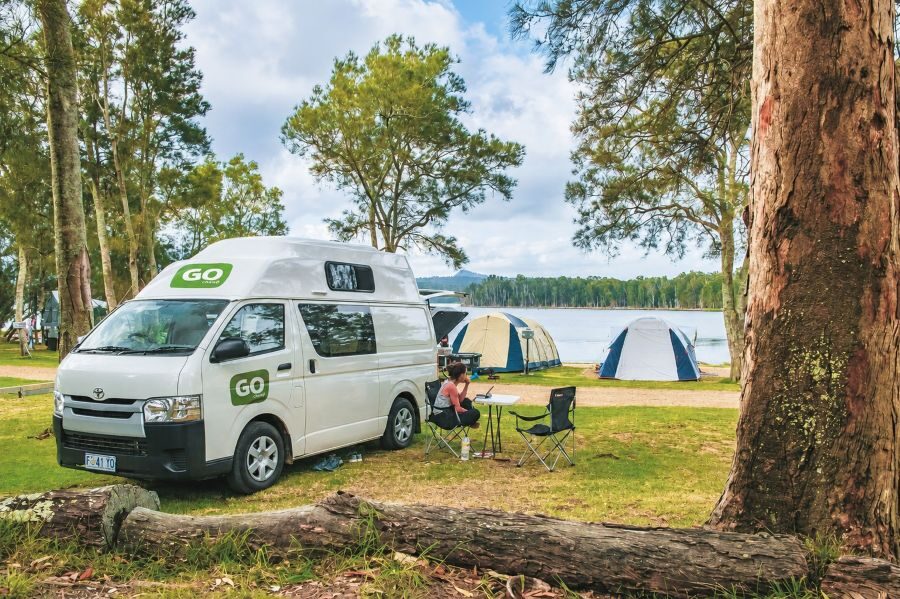 Twee mensen zitten buiten bij de Go Cheap 2 Berth Hitop op de camping
