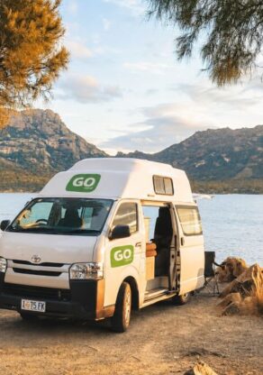 Go Cheap 4 berth Hitop staat geparkeerd aan zee met de zijdeur open