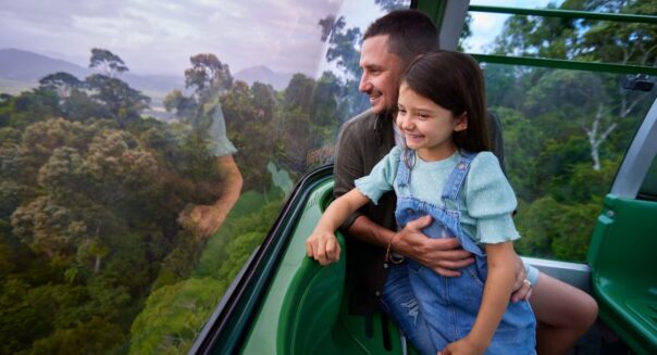 Vader en dochter kijken naar buiten vanuit de Kuranda Skyrail bij Cairns