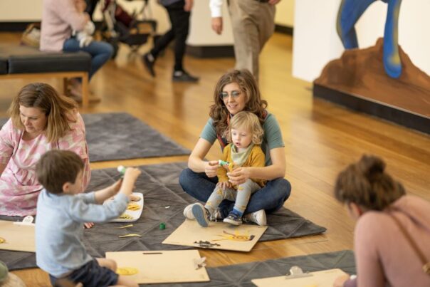Kinderen maken kunst in museum in Brisbane en zitten op de grond