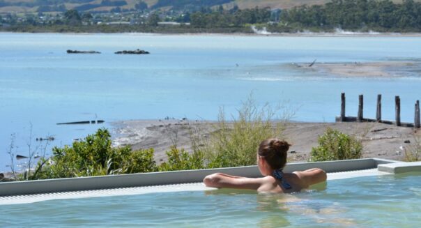 Jonge vrouw ligt in spa in Rotorua over het meer te kijken