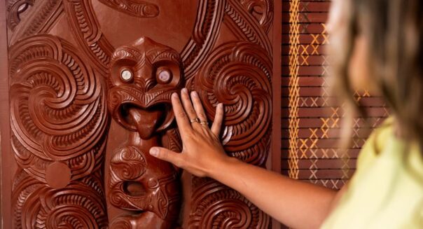 Vrouw raakt Maori houtsnijwerk aan in Rotorua