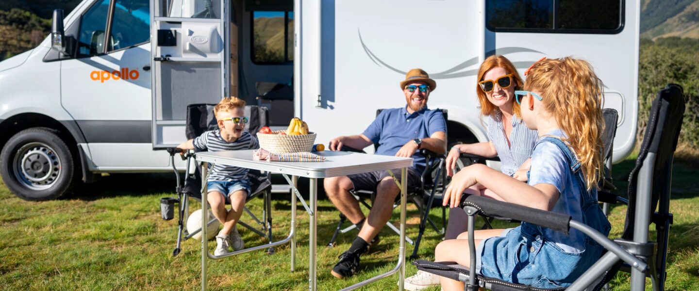 Gezin met jonge kinderen zit in campingset voor Apollo Euro Quest camper