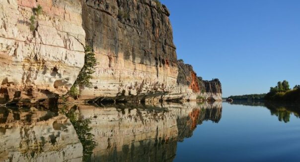 Zicht op gekleurde rotsen met reflectie in het water in de Geiki Gorge in de Kimberley