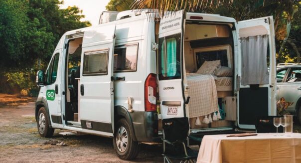 Go Cheap Tamar geparkeerd op een camping met de zij- en achterdeuren open en stoelen met tafel buiten
