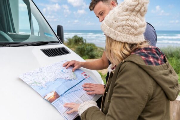 Koppel bekijkt wegenkaart op de motorkap van de camper op een frisse dag