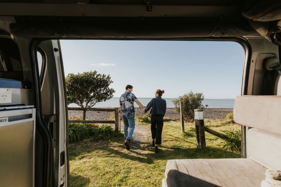 Zicht op een stel die naar het strand lopen vanuit de zijdeuren van de Jucy Chaser