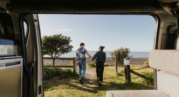 Zicht op een stel die naar het strand lopen vanuit de zijdeuren van de Jucy Chaser