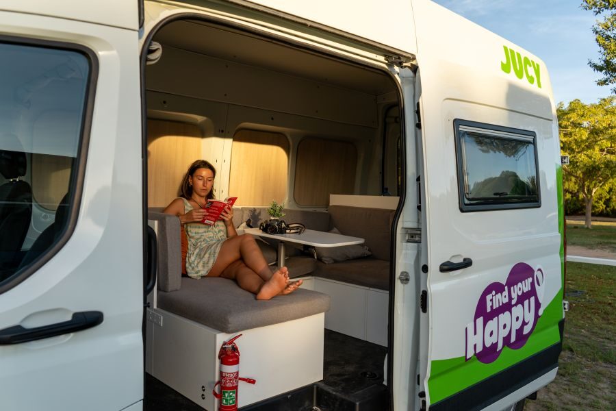 Vrouw leest een boek in de dinette van de Jucy Coaster