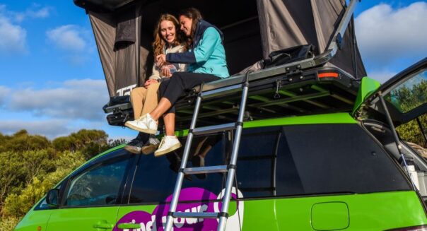 Twee vrouwen zitten in de daktent van de Jucy Crib Plus