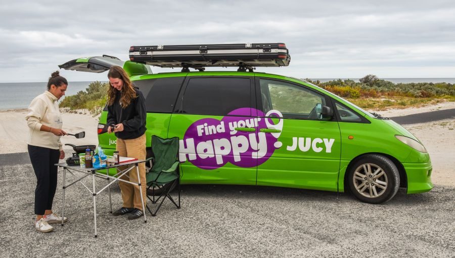 Twee vrouwen maken gebruik van de keuken en tafel van de Jucy Crib Plus aan het strand