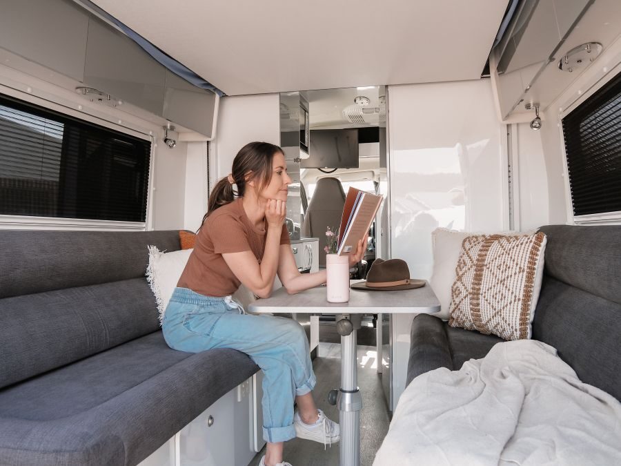 Een vrouw is een boek aan het lezen in de zithoek achterin de Star RV Polaris 2