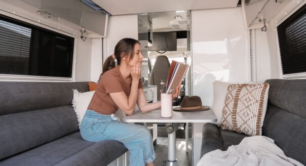 Een vrouw is een boek aan het lezen in de zithoek achterin de Star RV Polaris 2