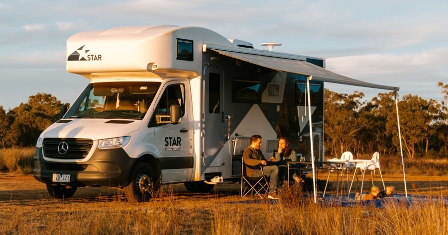 De luifel van de Star RV Polaris 6 is uitgeklapt en een gezin zit buiten