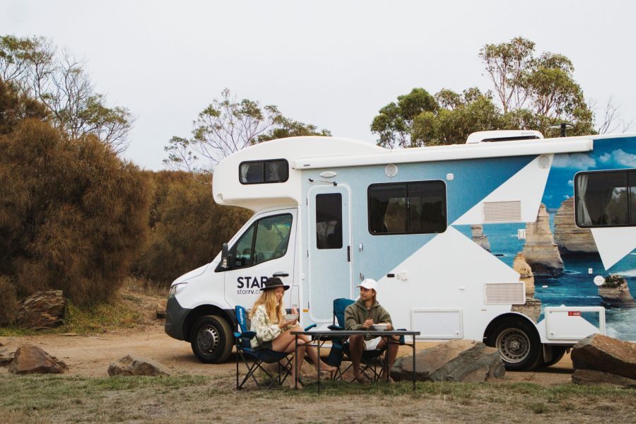 Star RV Polaris 6 is geparkeerd en een stel zit buiten aan tafel te eten