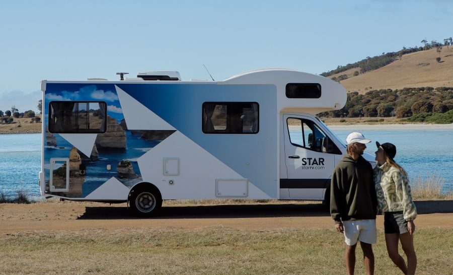 Een stel staat voor de Star RV Polaris 6 die geparkeerd staat aan het water