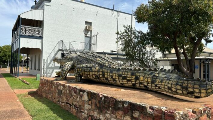 Beeld van de enorme krokodil Krys met op de achtergrond een historisch gebouw in Normanton
