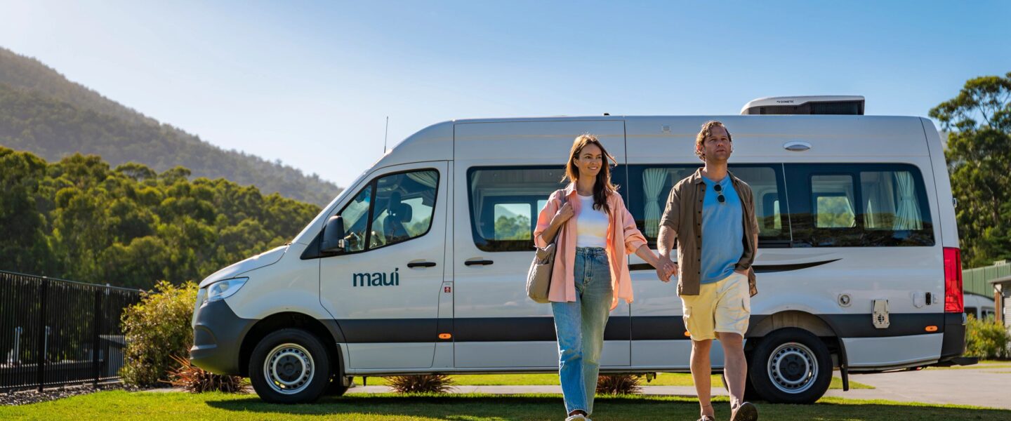Man en vrouw lopen hand in hand weg van de Maui Ultima camper in de Yarra Valley