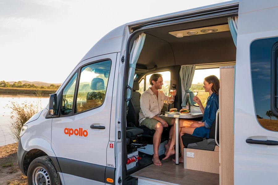 Een koppel is aan het dineren aan tafel met draaibare stoelen in de Apollo Endeavour camper in Australië