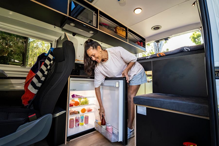 Vrouw maakt koelkast open in Britz Voyager camper