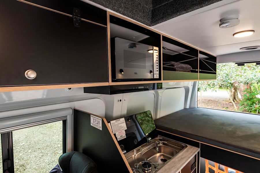 Britz Voyager Australië binnenkant van de camper met keukenblok en magnetron met zicht op het bed aan de achterkant inclusief open deuren